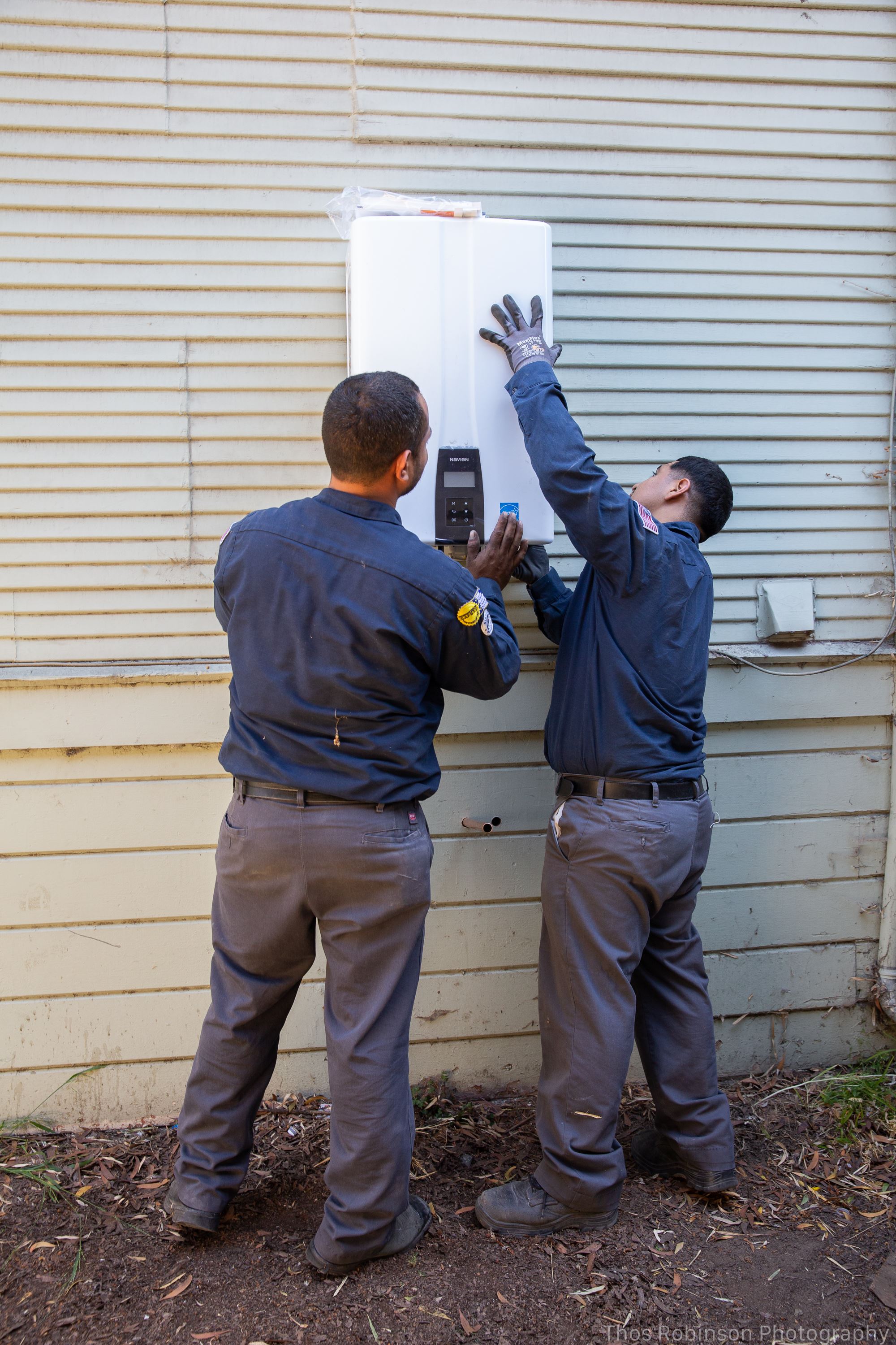 Plumbers from Big Blue Plumbing installing a tankless water heater in the Oakland area